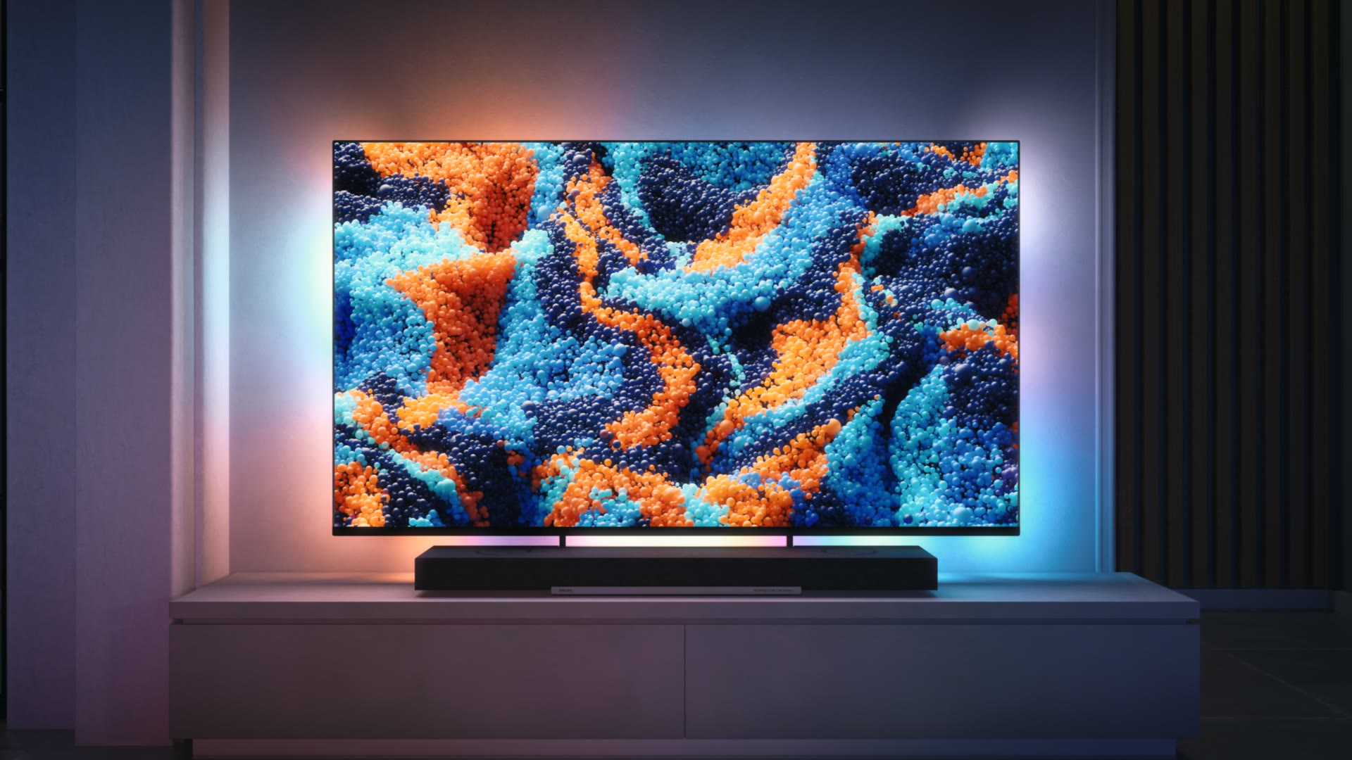 De televisie met een kleurrijk beeld tegen een donkere wand.